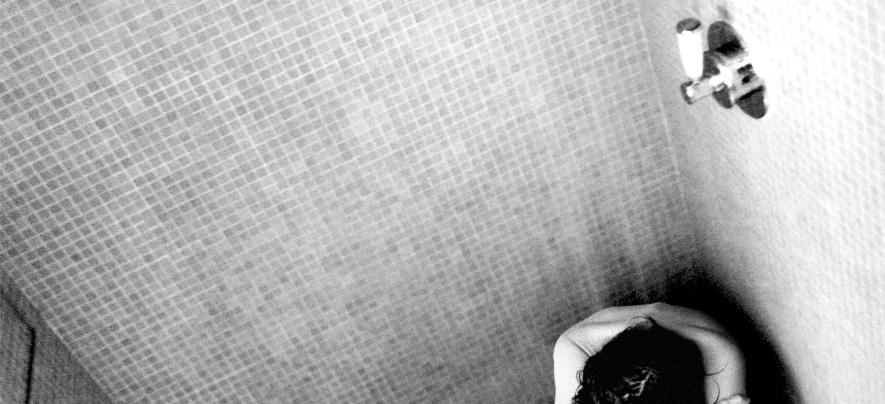 Inszenierte Schwarzweiß Fotografie. Frau sitzt zusammen gekauert nackt in der Dusche und lässt sich vom Wasser reinwaschen. Text: Ein Mädchen muss lieb sein. Ein Mädchen muss sich küssen lassen. Ein Mädchen muss ja sagen. Ein Mädchen muss mit Papa ins Bett. Es war furchtbar ein Mädchen zu sein. Wir helfen Opfern. Weisser Ring